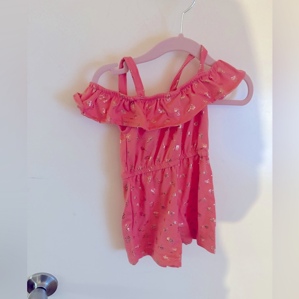 Coral romper with gold accents.